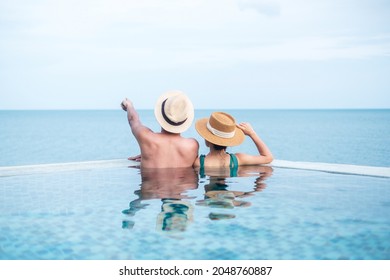 Happy couple in infinity pool at luxury hotel against ocean front., enjoy in tropical resort. Relaxing, summer,  travel, holiday, vacation , romance and weekend concept