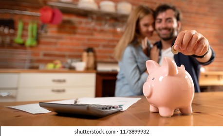 Happy Couple Inserting Coin In Piggybank. Home Budget, Family Finance Concept. Wide Photo With Space For Your Text