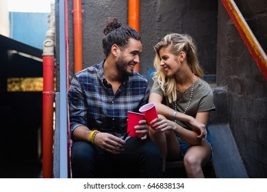 Happy couple interacting while having drink on staircase of bar - Powered by Shutterstock