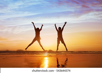 happy couple jumping on the beach at sunset, family summer holidays or honeymoon - Shutterstock ID 543644374