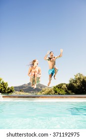 Happy Couple Jumping In The Pool In A Sunny Day