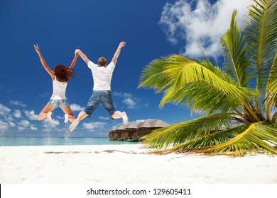 Happy Couple Jumping In The Tropical Beach