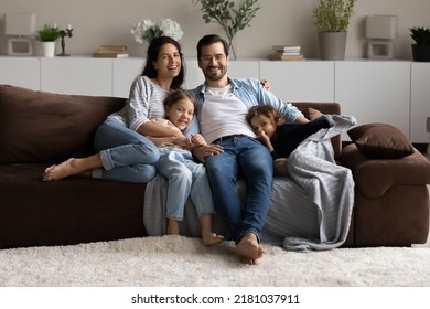 Happy couple and kids sit on sofa smiling look at camera. Preschool 5s girl, little 4s boy and parents relax together on couch posing photographing, capture moment. Well-being family portrait concept - Shutterstock ID 2181037911