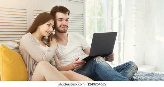 Happy couple with laptop on weekend morning
