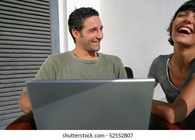 Happy couple laughing in front of a laptop computer - Shutterstock ID 52552807