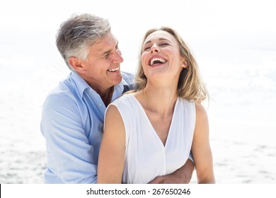 Happy couple laughing together at the beach - Powered by Shutterstock