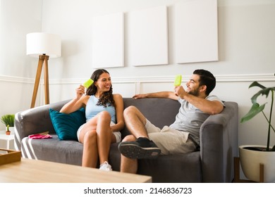 Happy couple laughing together while eating a cold ice pop during a hot summer