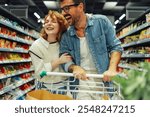 Happy couple laughs while shopping for groceries at a bright and clean supermarket, enjoying togetherness and making fun memories