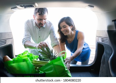 Happy Couple Loading Together Bags Of Groceries In Car Trunk