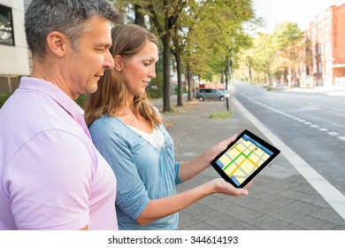 Happy Couple Looking At Gps Map On Digital Tablet
