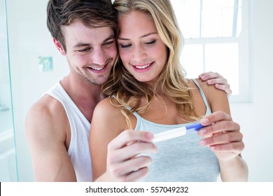 Happy Couple Looking At Pregnancy Test In Bathroom