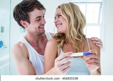 Happy Couple Looking At Pregnancy Test In Bathroom