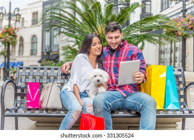 Happy Couple Looking At Tablet While Shopping - Boyfriend Embracing His Beautiful Girlfriend With Poodle In Beverly Hills - Rich Persons Having Fun