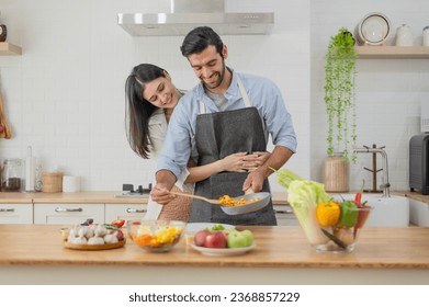 Happy couple in love cooking in the kitchen counter at home and hugging - Powered by Shutterstock