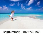 Happy couple in love is having fun and hugging on a sandbar with white sand and turquoise ocean