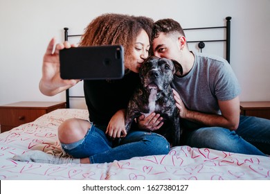 Happy Couple In Love At Home. Afro American Woman, Caucasian Man And Their Pit Bull Dog Together. Family Concept