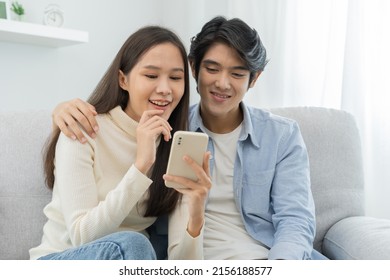 Happy Couple Love At Home,beautiful Two Asian Young Spending Good Time Together,bonding To Each Other And Smiling Romantic On Sofa In Living Room While Man Embrace Woman Using Smartphone, Mobile Phone