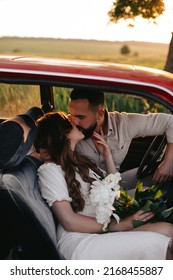 Happy Couple In Love Kissing While Sitting Together Inside A Red Retro Car On A Front Seat. 