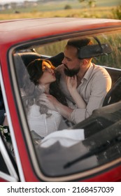 Happy Couple In Love Kissing While Sitting Together Inside A Red Retro Car On A Front Seat. 