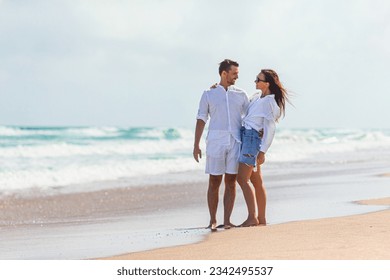 Happy couple in love on the beach vacation walking together at sunset. Young woman in white dress and caucasian man in white shorts. - Powered by Shutterstock