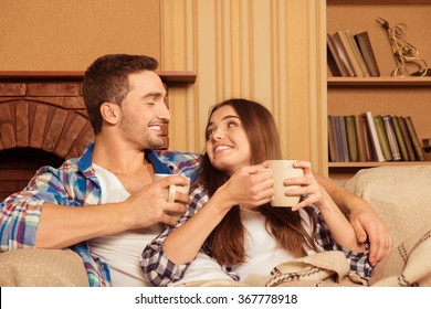 Happy Couple In Love With Plaid And Cups Relaxing On The Sofa