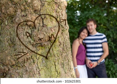 Happy Couple In Love With Their Initials Carved In A Tree