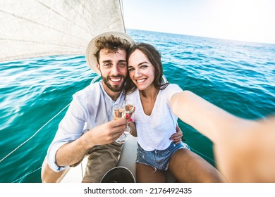 Happy couple of lovers enjoying sail boat trip experience in the ocean - Boyfriend and girlfriend taking selfie picture outside on summer vacation  - Powered by Shutterstock