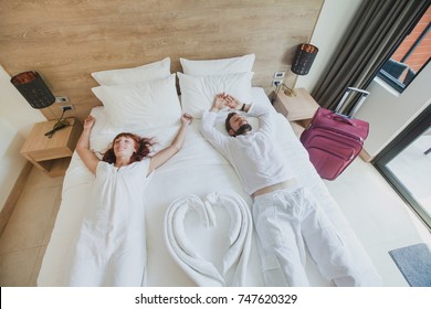 Happy Couple In Luxury Hotel Room, Holidays Travel Accommodation, Top View Of Smiling Man And Woman Lying Down On The Bed