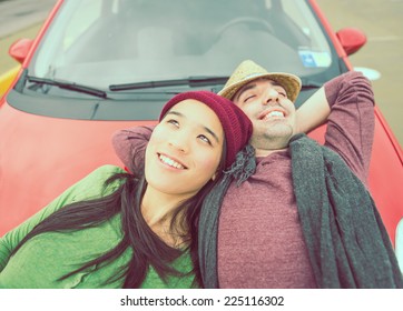 Happy Couple Lying On The Car Hood. Concept Of Carefree And Relaxation