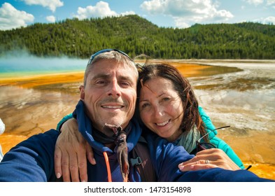 Happy Couple Making A Selfie With The Background Of Grand Prismatic Spring Geyser, Yellowstone National Park.