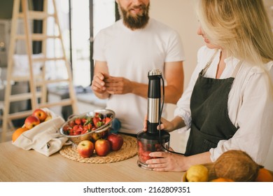 Happy Couple Making Smoothies Using Blender And Fresh Fruits On The Kitchen. Healthy Food.