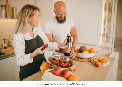 Happy Couple Making Smoothies Using Blender And Fresh Fruits On The Kitchen. Healthy Food.