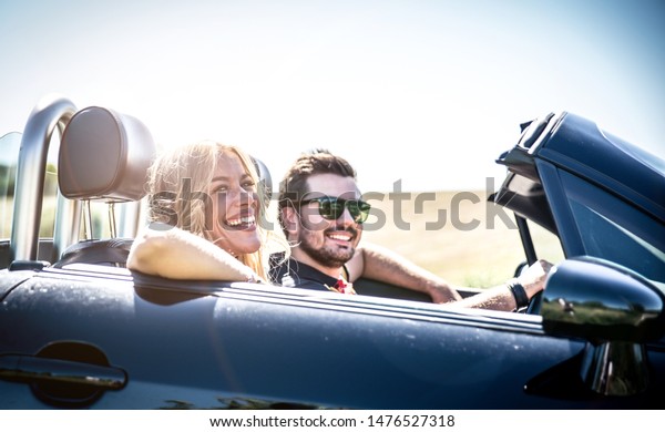 Happy couple making a tour in\
central italy. Driving on a convertible car in the italian\
countryside 