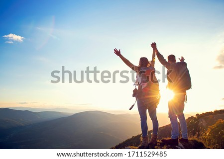 happy couple man and woman tourist at top of mountain at sunset outdoors during a hike in summer