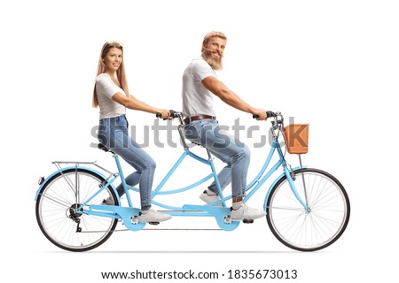Happy couple in matching outfits riding a tandem bicycle isolated on white background