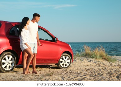 Happy Couple Near Car On Sandy Beach, Space For Text. Summer Trip