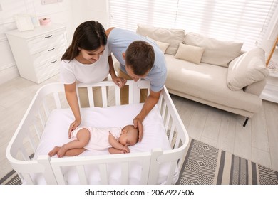 Happy couple near crib with their cute baby at home - Powered by Shutterstock