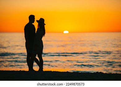Happy couple on the beach at beautiful sunset on background