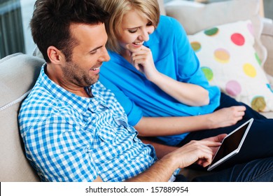 Happy Couple On Couch With Digital Tablet