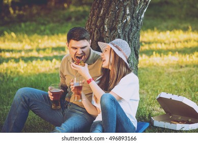 Happy couple on picnic in the park. Eating pizza and drinking beer. - Powered by Shutterstock