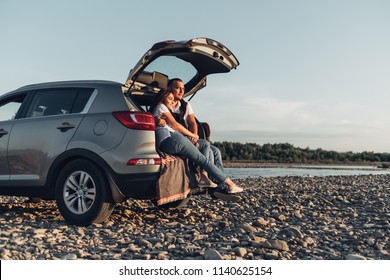 Happy Couple On Roadtrip Into The Sunset In SUV Car