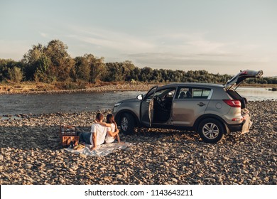 Happy Couple On Roadtrip Into The Sunset In SUV Car