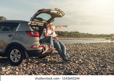 Happy Couple On Roadtrip Into The Sunset In SUV Car