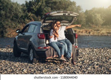 Happy Couple On Roadtrip Into The Sunset In SUV Car