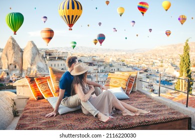 Happy couple on a rooftop in Cappadocia with hot air balloons in the background. Hot air balloon flights in Turkey - Shutterstock ID 2116220030
