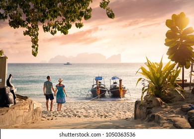 Happy couple on the tropical beach of Phi Phi island at sunset in Southern Thailand. Travel magazine concept.