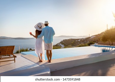 Happy couple on vacation time enjoys the summer sunset by the pool with an aperitif drink - Powered by Shutterstock