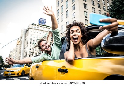 Happy couple on a yellow cab in New york. Afro american woman and her boyfriend taking a selfie with the smartphone