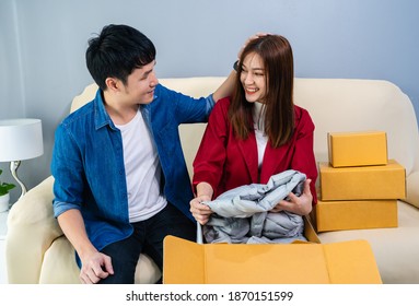 Happy Couple Open A Cardboard Parcel Box In The Living Room At Home, Purchase On Online Store