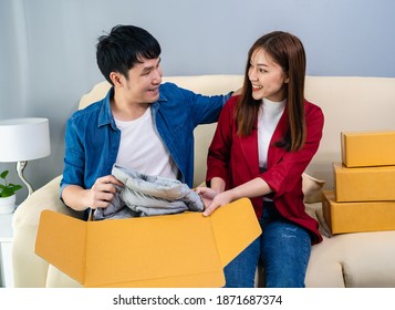 Happy Couple Open A Cardboard Parcel Box In The Living Room At Home, Purchase On Online Store